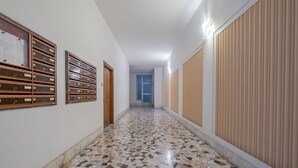 A hallway with a tiled floor, wooden lockers, and a blue door at the end. - Basilica of St. John Lateran • 1Bedr - 5 minutes Station A/C (Roma)