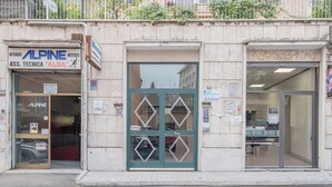 A building with a storefront labeled 'ALPINE ASS. TECNICA ALBA' and a barber shop across the street. - Basilica of St. John Lateran • 1Bedr - 5 minutes Station A/C (Roma)