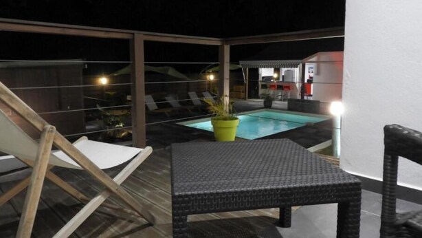 An outdoor pool area with a lounge chair, a small table, and a potted plant. - Résidence KAZ A Bibi - Flamboyant (Sainte-Rose)