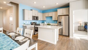 A modern kitchen with white cabinets, stainless steel appliances, and a central island.