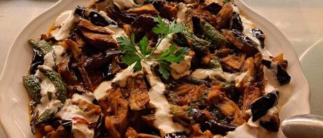 Prato de comida com diversos vegetais e um enfeite, sobre uma mesa com uma cesta de palha e uma tigela ao fundo.