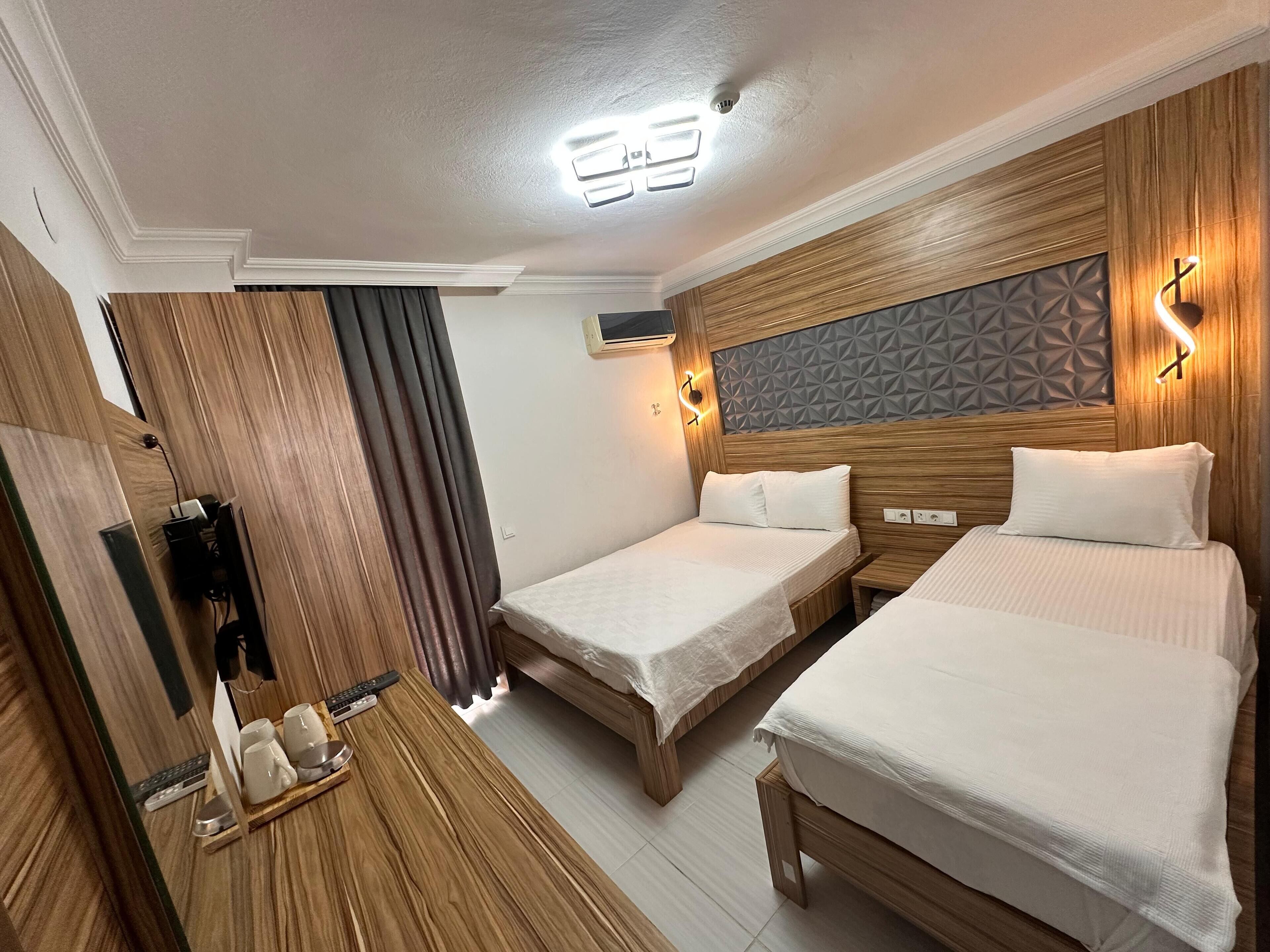 A hotel room with two beds, wooden paneling, a geometric wall design, and a mirror with a power strip.