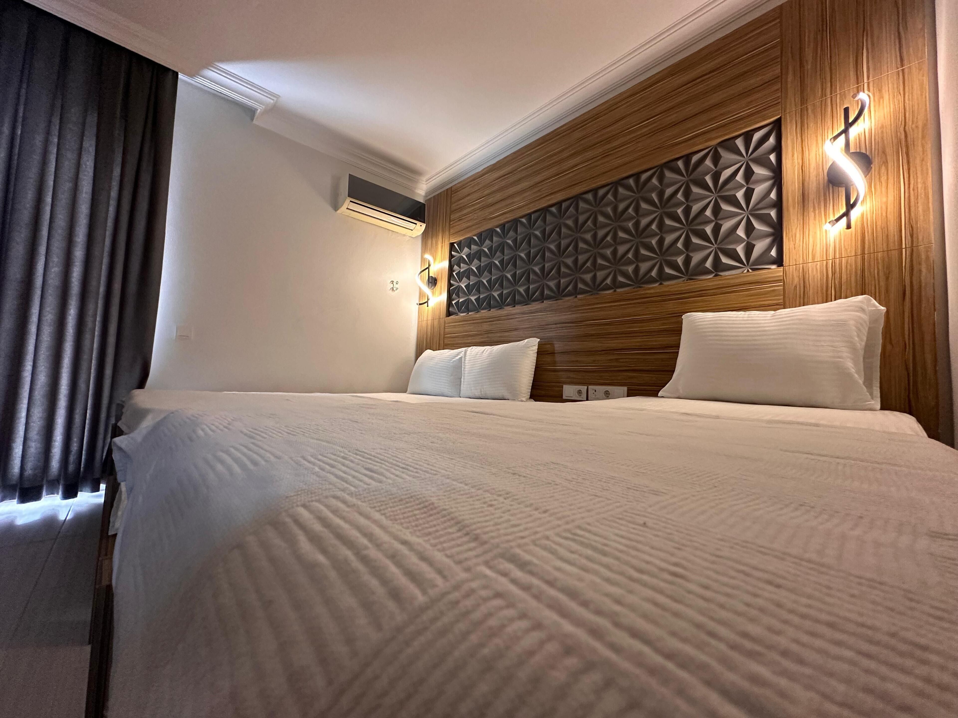 A hotel room with a large bed, wooden headboard, and geometric wall paneling.