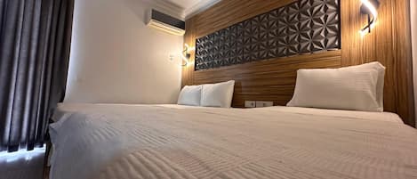 A hotel room with a large bed, wooden headboard, and geometric wall paneling.