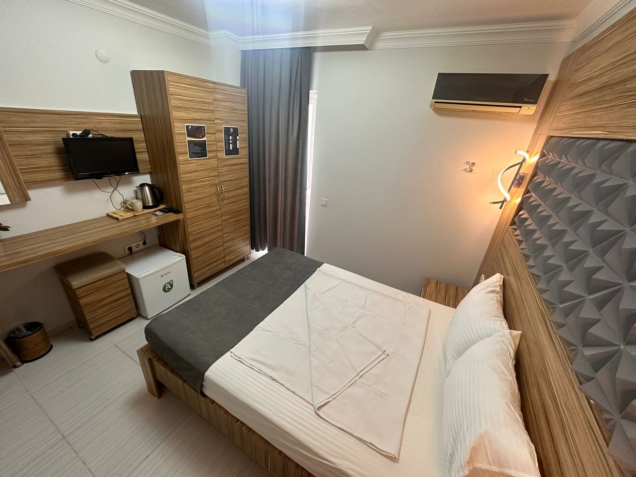 A hotel room with a bed, a desk, a television, and a wardrobe.