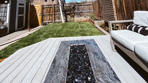 A backyard with a wooden deck, a small shed, a garden area, and a wooden fence.
