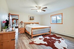 A bedroom with a wooden bed, a ceiling fan, a window, and a cowhide rug. - Trinity Springs ~ Mountain Oasis (Jemez Springs)
