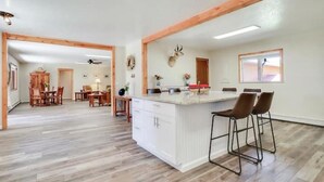 Eine geräumige Küche mit einer zentralen Kochinsel, Holzbalken und einem Essbereich mit Holztisch und Stühlen.