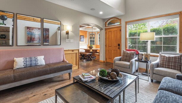 Amplia sala de estar con un sofá de cuero marrón, una mesa de centro con objetos decorativos y un comedor con muebles de madera.