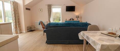 A cozy room with a bed, a dining table, and a TV.