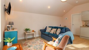 A cozy living room with a blue sofa, a wooden chair, a small table with a bowl, and a patterned rug. - Y Felin (Caernarfon)
