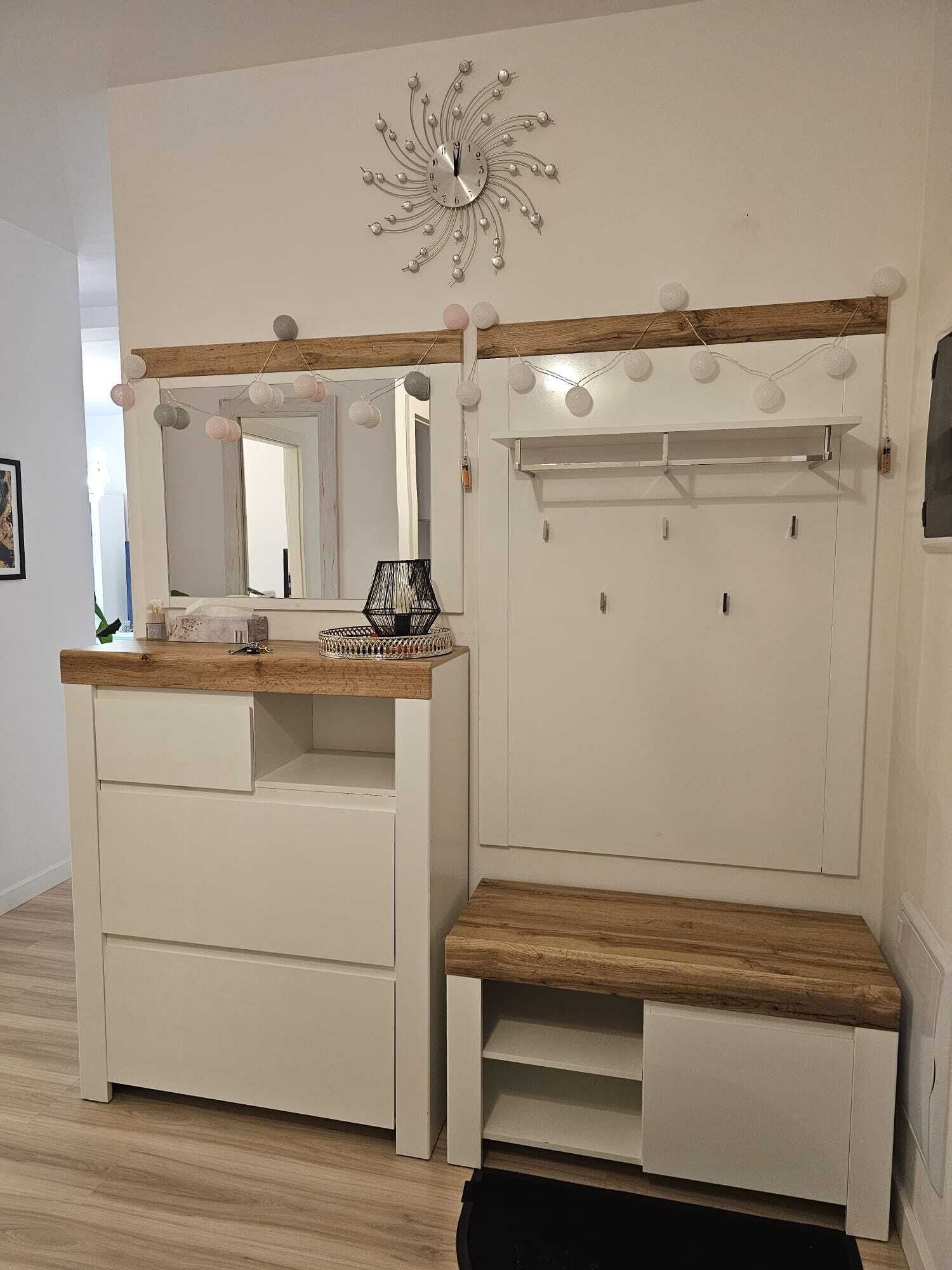 A white vanity with a mirror, wooden top, and drawers.