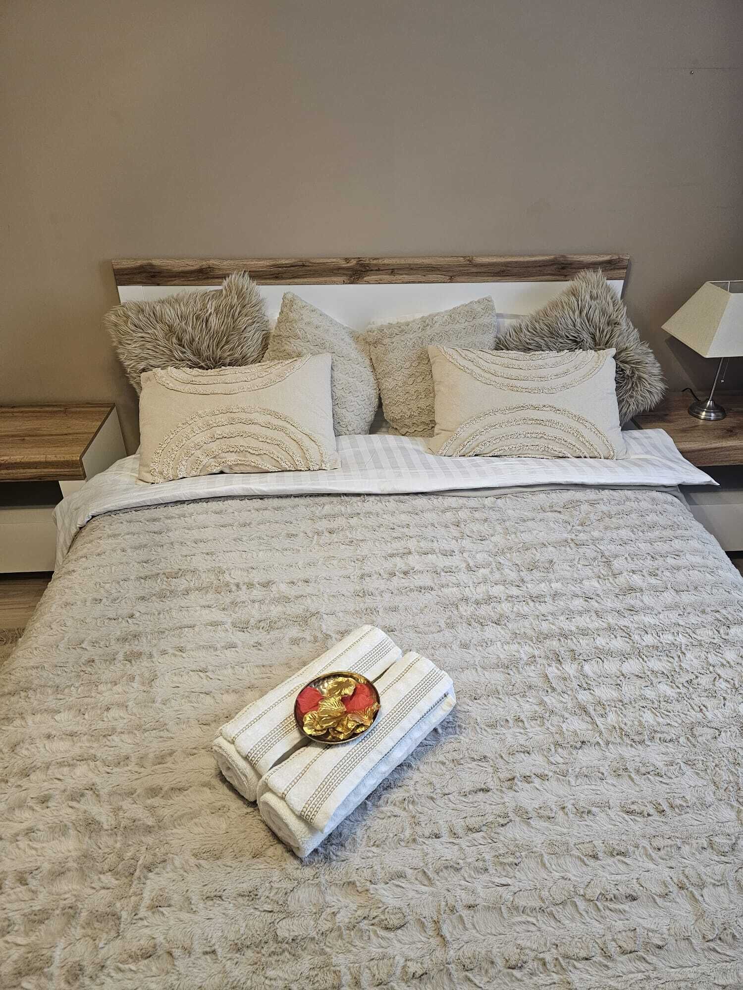 Una cama bien hecha con un edredón estampado, varias almohadas y un adorno sobre la cama.