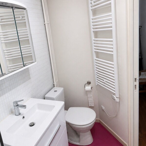 A bathroom with a white sink, toilet, and towel rack.
