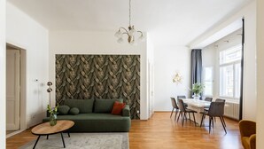 A modern living room with a sofa, a dining table, and a chandelier.