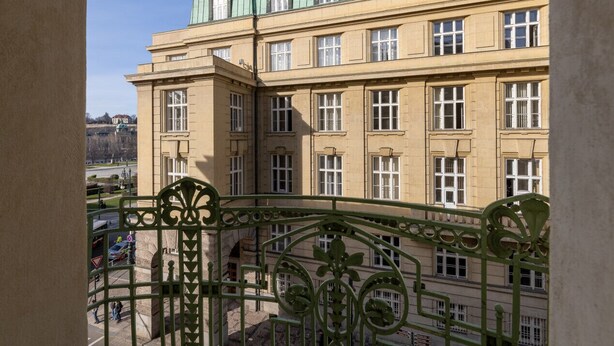 A multi-story building with a classic architectural style, featuring large windows and a green roof.