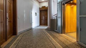 A hallway with wooden doors, a marble floor, and a large column.