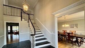 Un interior espacioso con una escalera, un comedor y vistas al exterior.