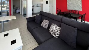 Una sala de estar moderna con un sofá oscuro, una mesa blanca y paredes rojas de acento.