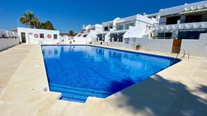 Una piscina con agua azul cristalina, rodeada de edificios blancos con balcones.