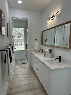A modern bathroom with a large mirror, two sinks, and a walk-in shower. - Entire New modern Home in Naples (Naples)