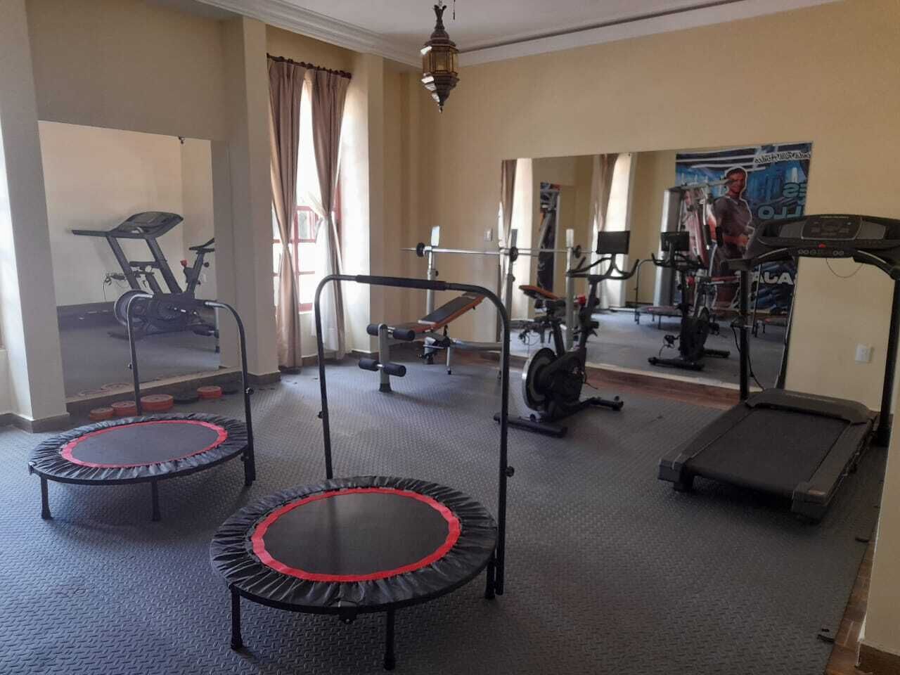 A home gym with two trampolines, a treadmill, and a stationary bike.