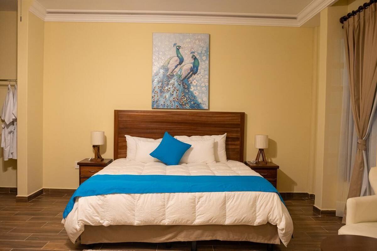 A neatly made bed with a blue accent pillow, wooden headboard, and two bedside lamps.
