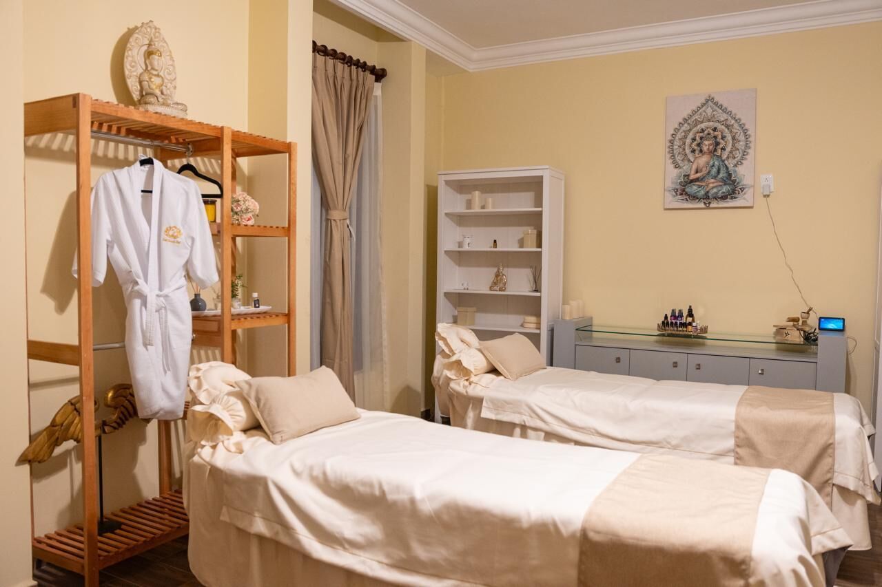 A room with two beds, a robe rack, a shelf with toiletries, and a Buddha statue.