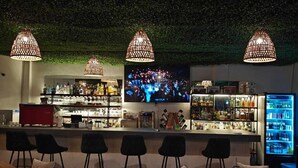 Un espace bar avec des sièges, un écran de télévision et un réfrigérateur.