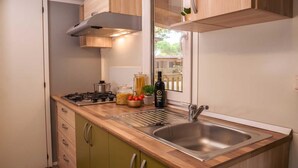 A modern kitchen with a stainless steel sink, wooden countertop, and green cabinets.