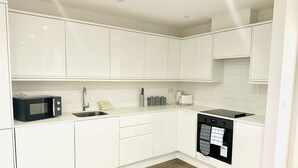 A modern kitchen with white cabinetry, a microwave, a sink, a toaster, and a dishwasher. - Spacious Margate Apartment- Beach,arts&high Street (Margate)