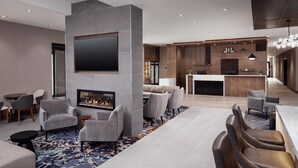 Un moderno vestíbulo de hotel con chimenea, zona de estar y bar.