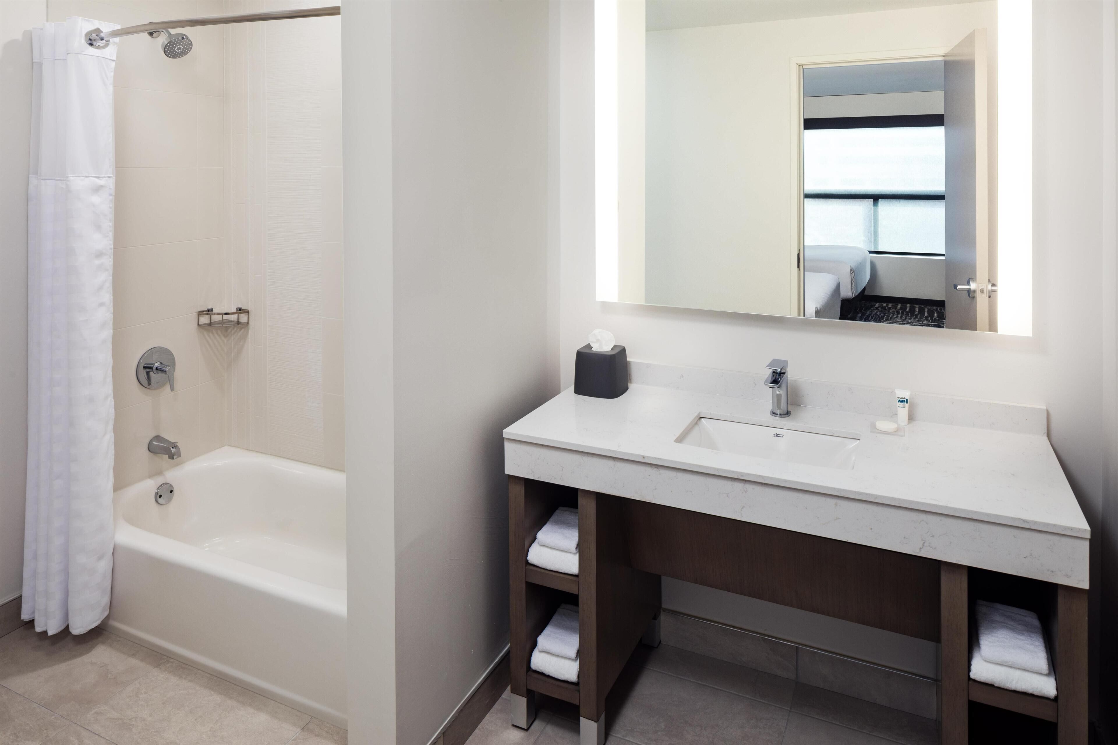 A modern bathroom with a bathtub, a sink, and a mirror.