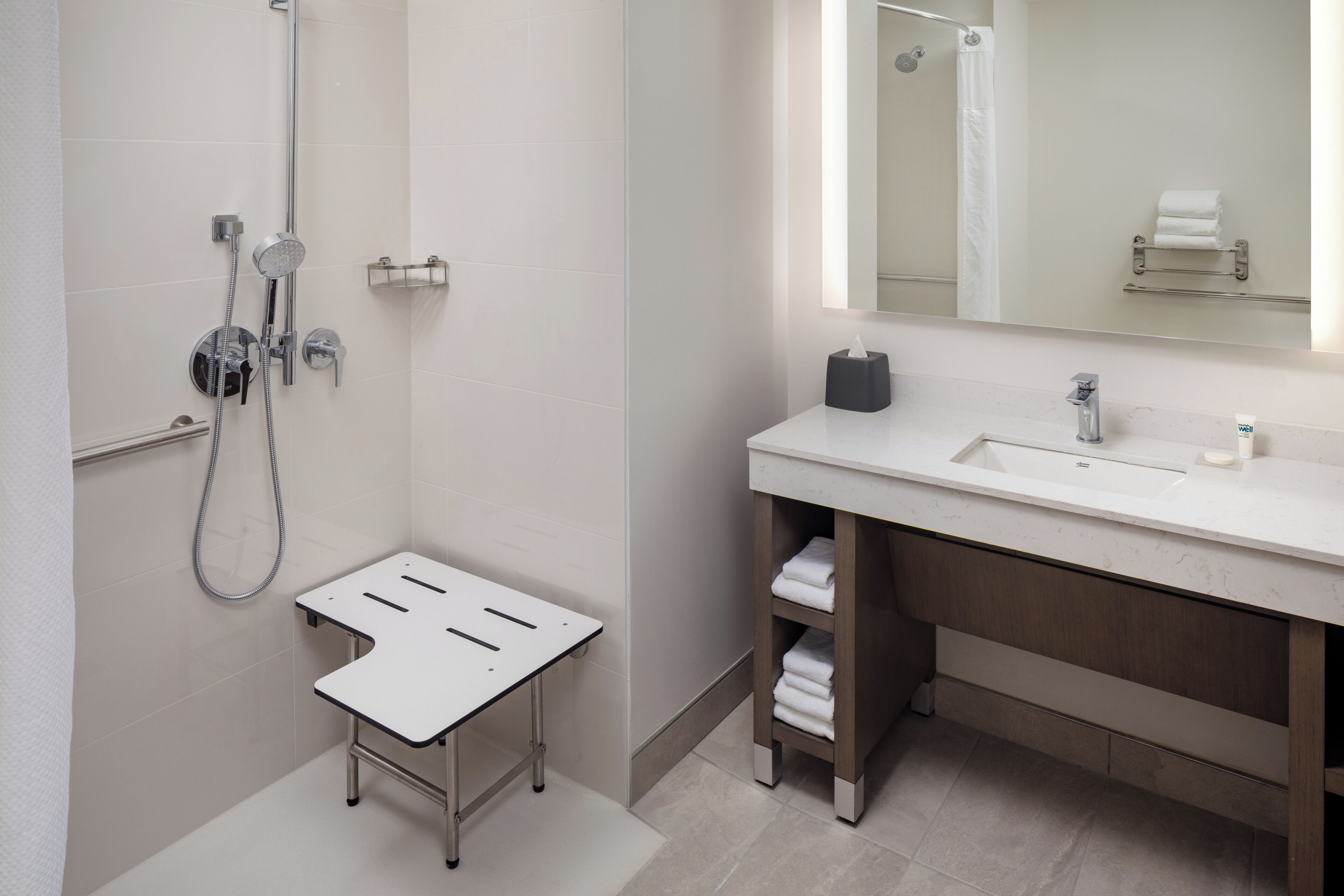 A modern bathroom with a shower, a sink, and a mirror.