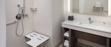 A modern bathroom with a shower, a sink, and a mirror.