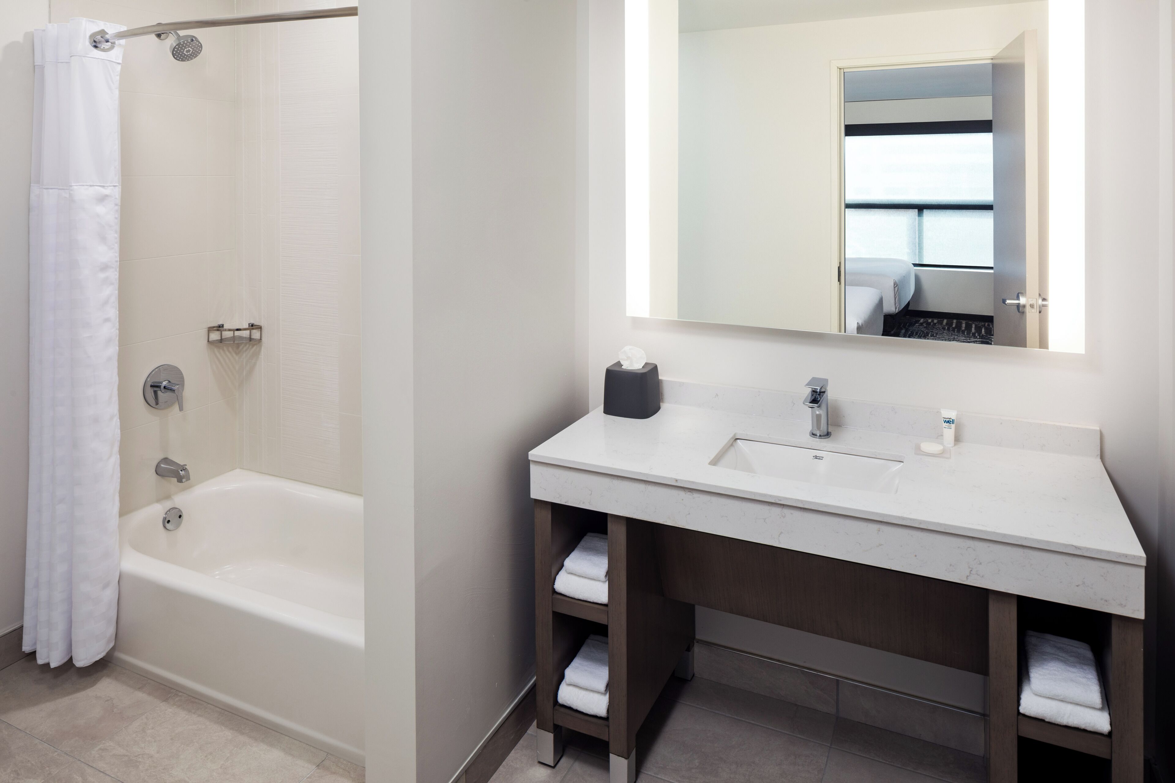 A modern bathroom with a bathtub, a sink, a mirror, and a shower curtain.