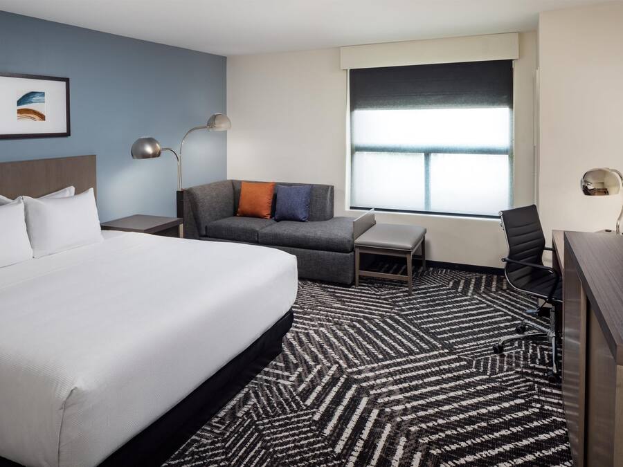 A hotel room with a large bed, a sofa, a desk, and a chair.