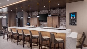 Un moderno bar con una barra larga, varios taburetes y luces colgantes, con un letrero que indica que es un bar.