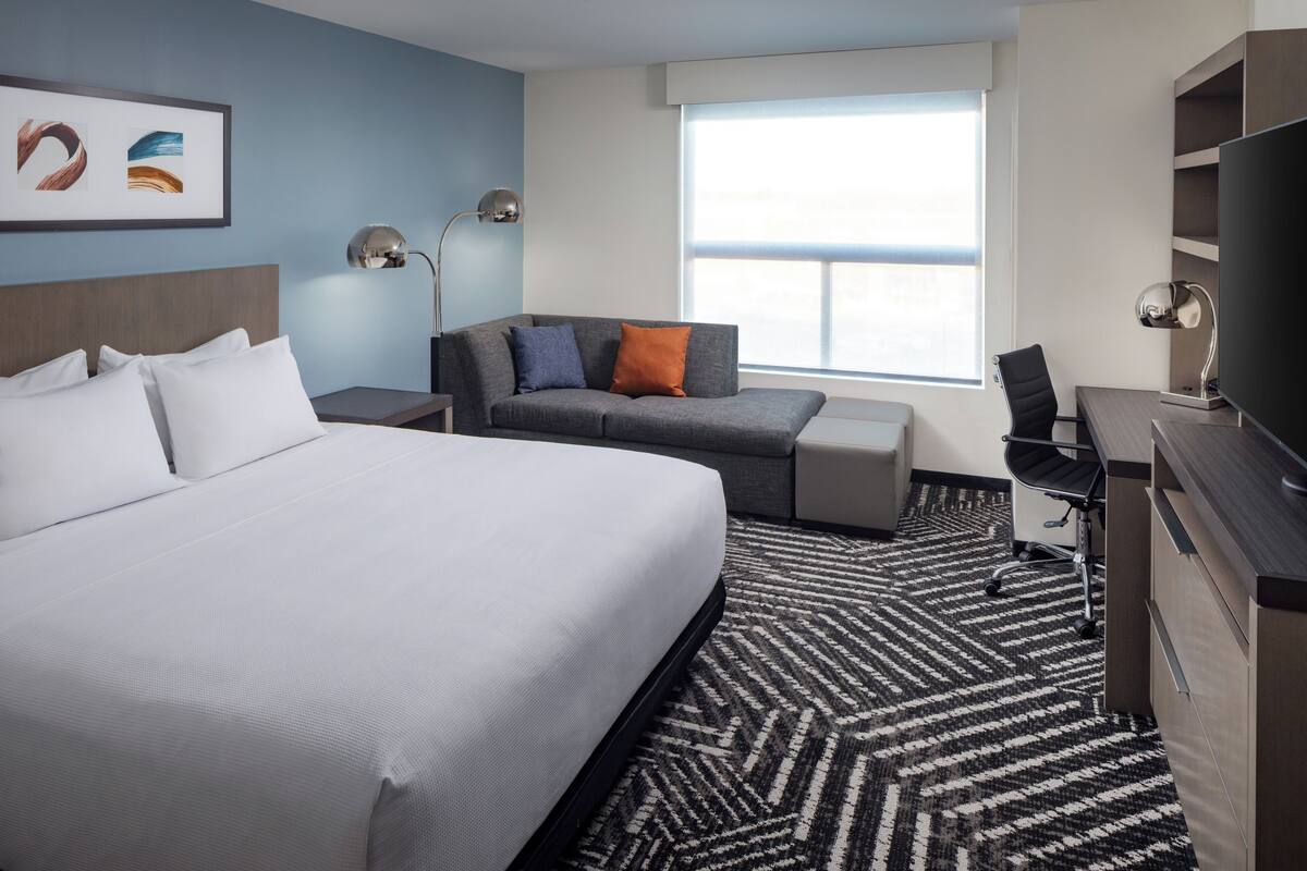 Una habitación de hotel con una cama grande, un sofá, un escritorio y un televisor.