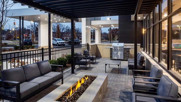 Un patio al aire libre con una chimenea, asientos y una zona de parrilla.