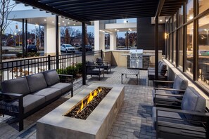 Un patio al aire libre con una chimenea, asientos y una zona de parrilla.