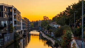 A canal with buildings on both sides, a pedestrian path, and a clear sky. - Canal View House | 2BR with Garden & Parking (London)