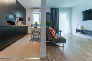 Enjoy a comfortable stay in this apartment with a sleek kitchen, compact dining area, and a large window with sheer curtains.