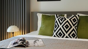 Ein ordentlich bezogenes Bett mit einer Zeitschrift, Kissen und einer Lampe.