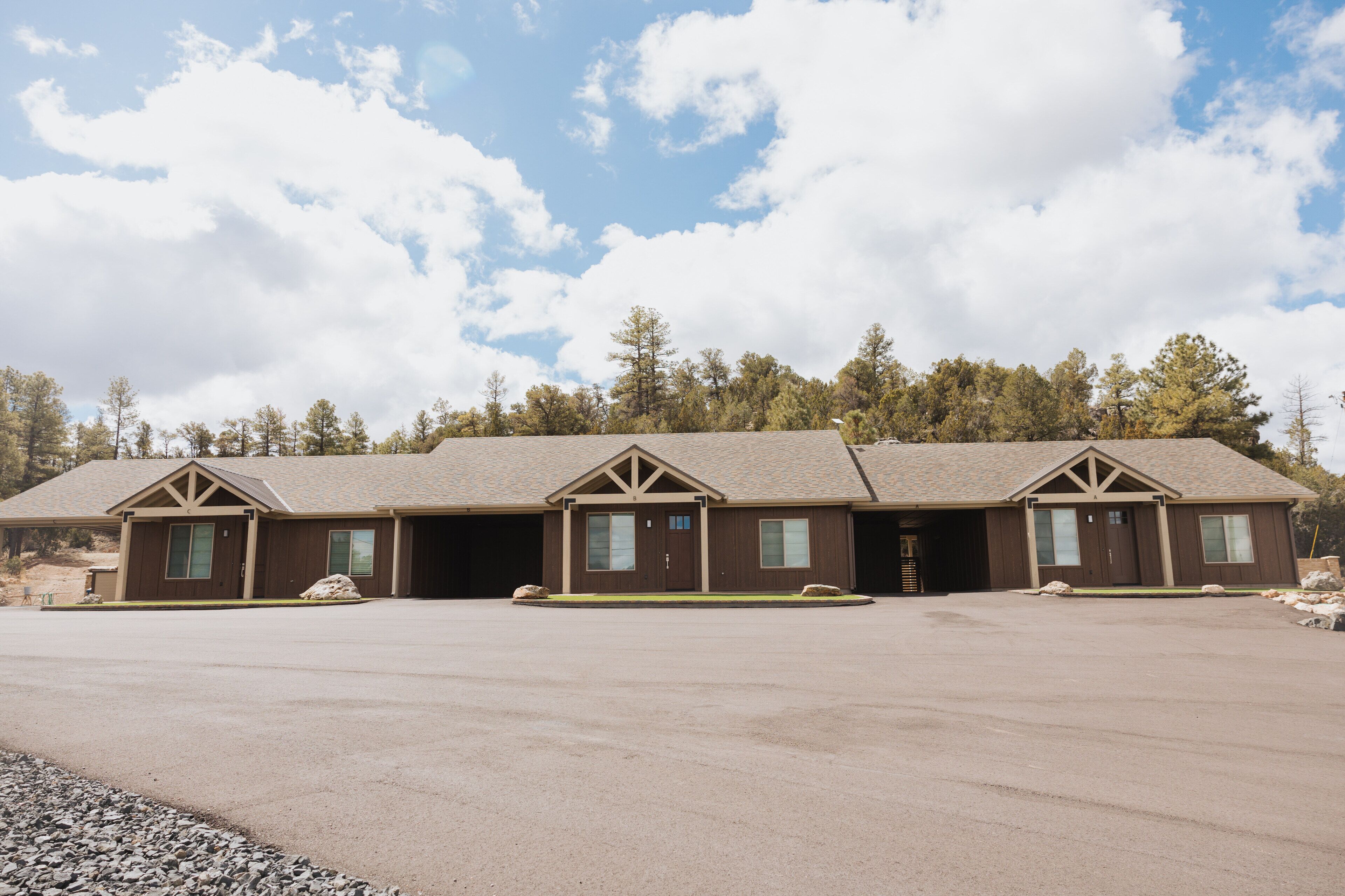 A row of three single-story buildings with a flat roof, each with a front door and windows.