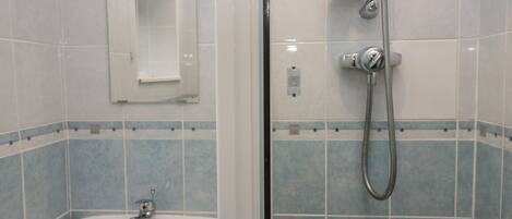Een badkamer met een wastafel, spiegel en douche met een doucheslang.