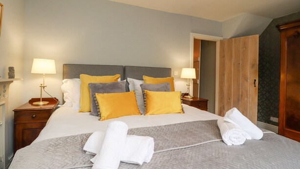 A hotel room with a bed, two bedside tables, and a wardrobe. - Riverdale House (Skipton)