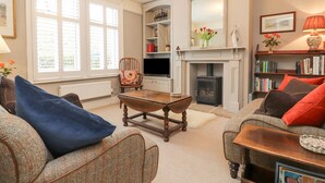 A cozy living room with a fireplace, a television, and a bookshelf. - Riverdale House (Skipton)