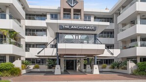 Ein modernes Hotel mit einem gut sichtbaren Anker-Logo, mehreren Balkonen und einem klaren Eingang.