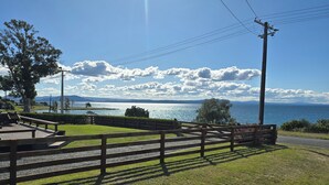 Un parque con bancos de madera, una zona verde y vistas a un lago con montañas al fondo.